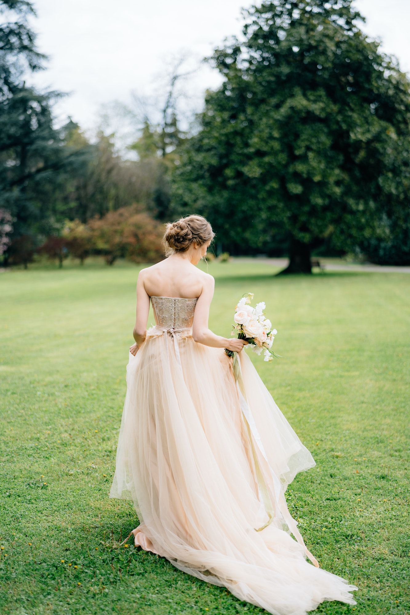 bride-in-a-beautiful-dress-with-a-bouquet-of-flowers-is-walking-in-a-green-park-lake-como-back.jpg